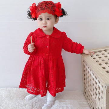 A newborn baby girl dressed in an elegant red full moon dress with lace details and a bow.
