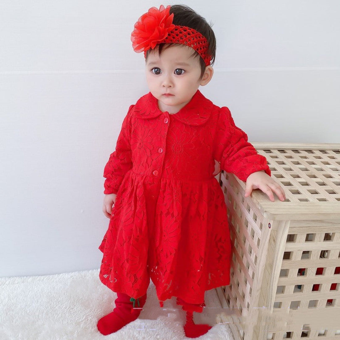 Lace detail on a red newborn baby girl dress, highlighting its intricate design.