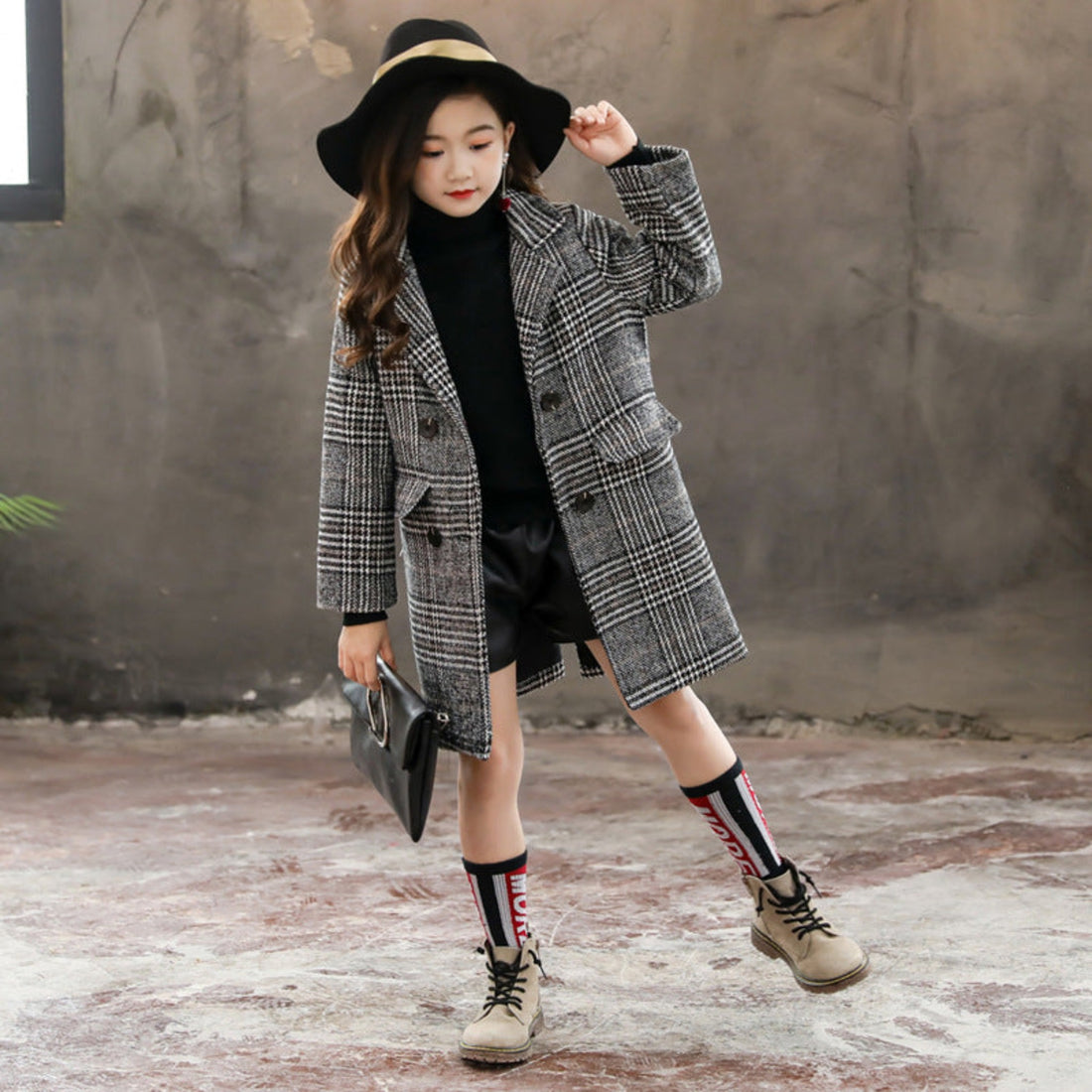 A girl staying warm in a gray plaid houndstooth coat during winter.