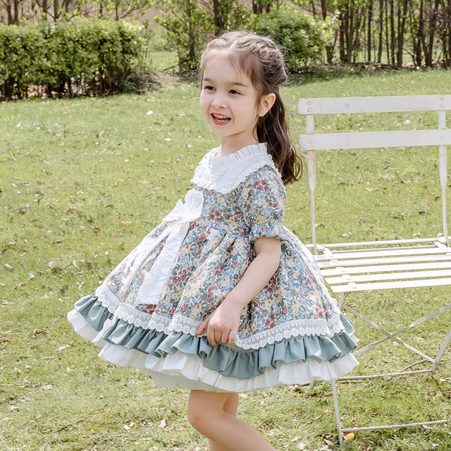 A baby girl smiling in an adorable floral dress, ideal for warmer days.